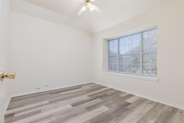 unfurnished room with baseboards, light wood-style floors, and vaulted ceiling