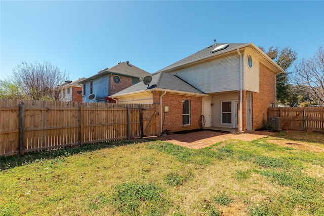 back of property featuring a patio, a fenced backyard, central AC, a lawn, and brick siding