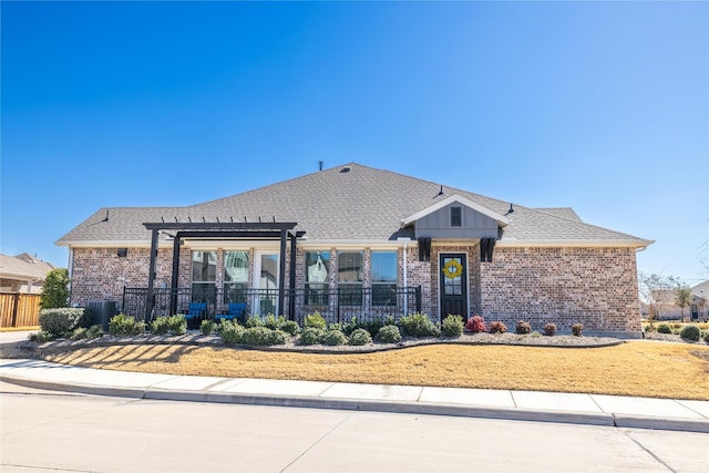 view of front of house featuring brick siding, fence, a pergola, and a shingled roof