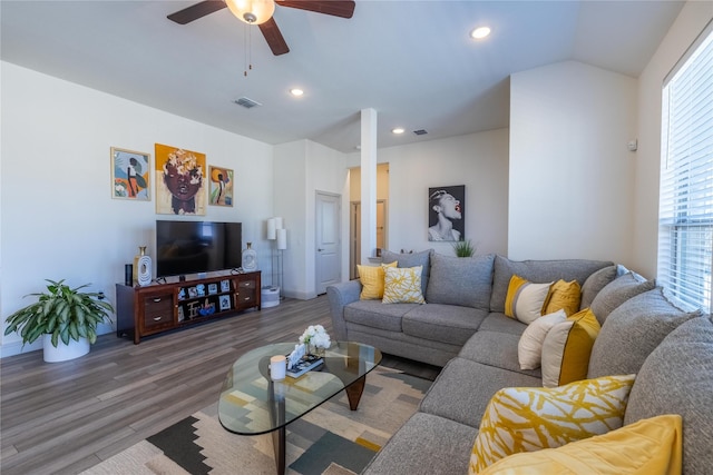 living area featuring a ceiling fan, vaulted ceiling, wood finished floors, and visible vents