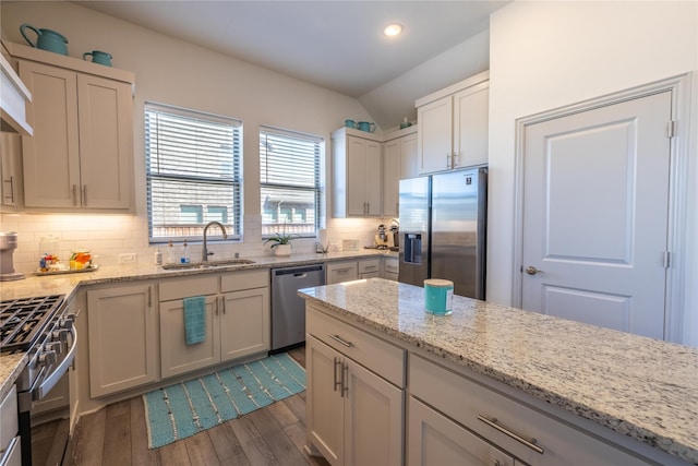 kitchen with dark wood-style floors, lofted ceiling, a sink, appliances with stainless steel finishes, and backsplash