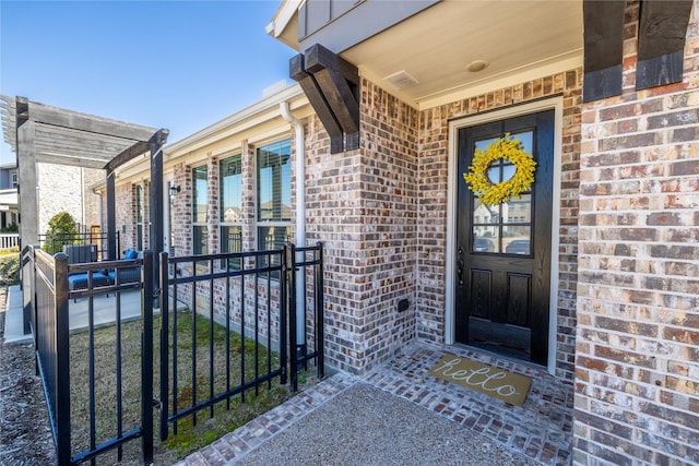 doorway to property featuring brick siding and fence