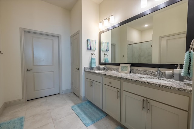 full bathroom with tile patterned floors, double vanity, a stall shower, and a sink