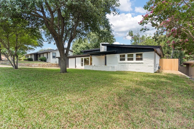 mid-century home featuring brick siding, a front yard, and fence