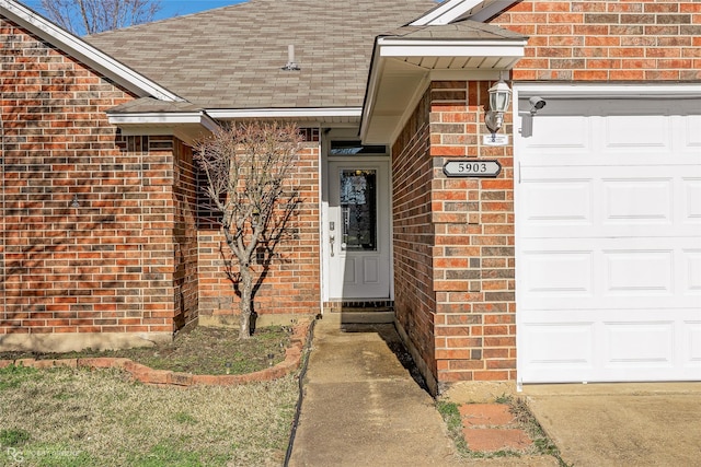 property entrance with an attached garage, brick siding, and roof with shingles