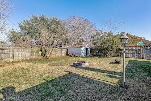 view of yard featuring a storage unit, a fire pit, a fenced backyard, and an outdoor structure