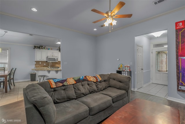 living room with a ceiling fan, baseboards, visible vents, recessed lighting, and crown molding