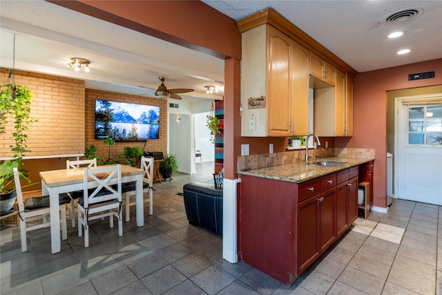 1306 N Floyd Rd, Richardson, TX 75080 - kitchen featuring visible vents, brick wall, ceiling fan, a sink, and a textured ceiling