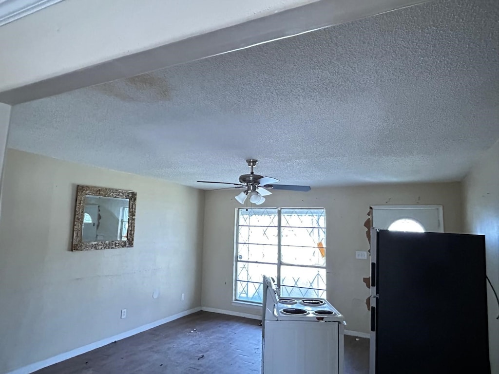 kitchen with a textured ceiling, baseboards, freestanding refrigerator, and ceiling fan