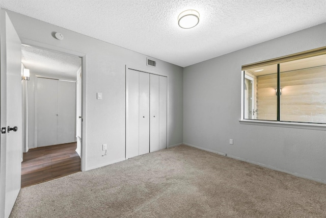 unfurnished bedroom with a closet, visible vents, carpet flooring, and a textured ceiling