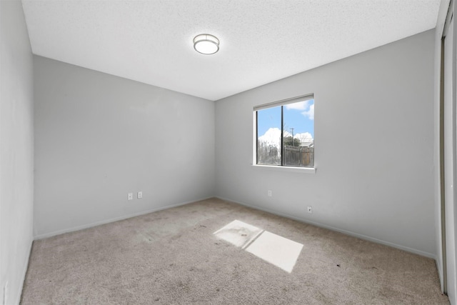 carpeted spare room with baseboards and a textured ceiling