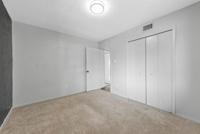 unfurnished bedroom featuring a closet, visible vents, a textured ceiling, and carpet floors