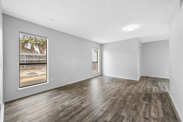 spare room featuring dark wood finished floors, visible vents, a textured ceiling, and baseboards