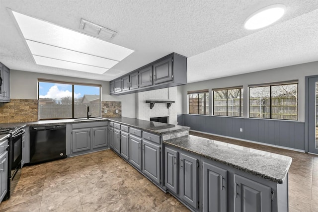 kitchen with black appliances, gray cabinetry, a sink, backsplash, and a peninsula