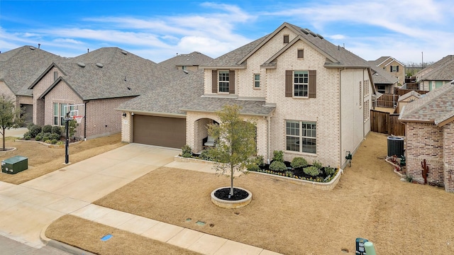 french provincial home featuring brick siding, an attached garage, driveway, and a shingled roof