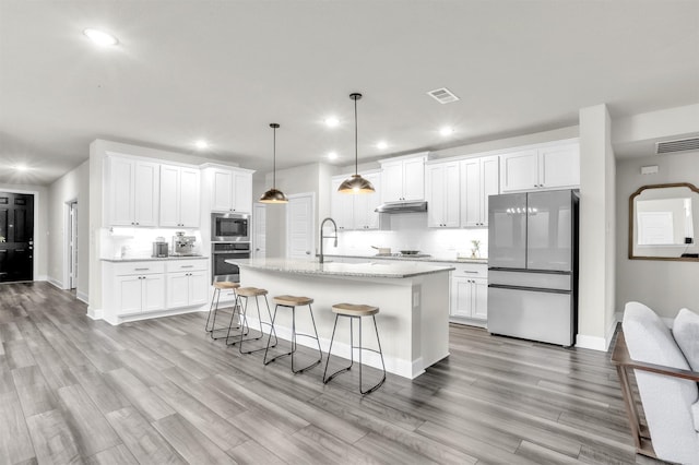 kitchen with visible vents, a sink, white cabinets, under cabinet range hood, and appliances with stainless steel finishes