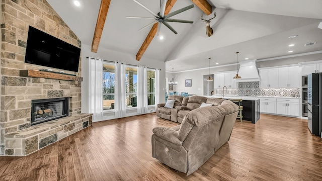 living room featuring light wood-type flooring, beamed ceiling, high vaulted ceiling, visible vents, and a fireplace