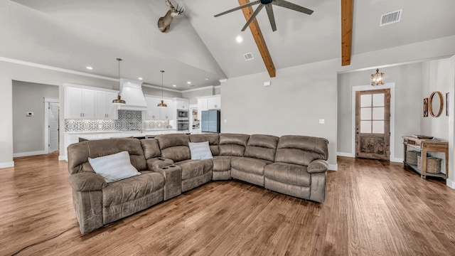 living room with visible vents, light wood-style floors, and beamed ceiling