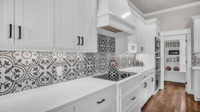 kitchen featuring light countertops, custom range hood, crown molding, black electric cooktop, and tasteful backsplash