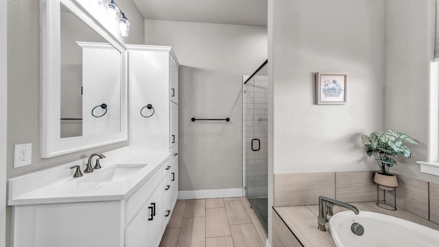 bathroom featuring a bath, a shower stall, vanity, and baseboards