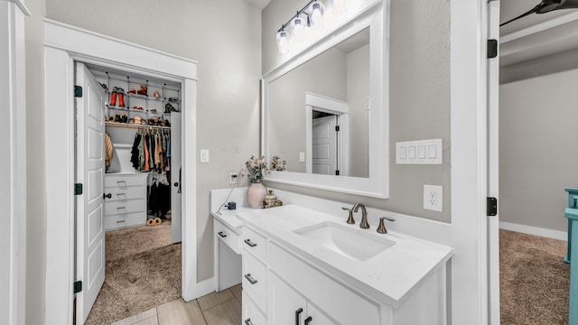 bathroom featuring vanity, a spacious closet, and baseboards