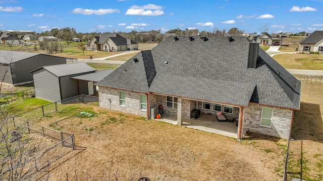 back of property featuring a residential view, a patio, fence, and a shingled roof