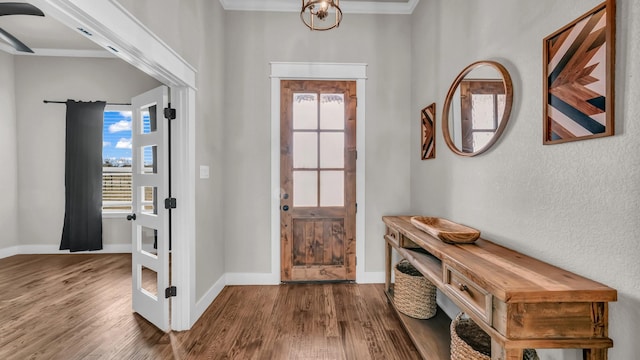 foyer with an inviting chandelier, wood finished floors, baseboards, and ornamental molding