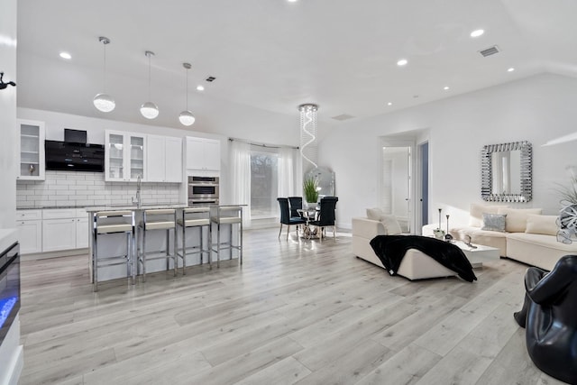 living room featuring light wood finished floors, visible vents, recessed lighting, and lofted ceiling