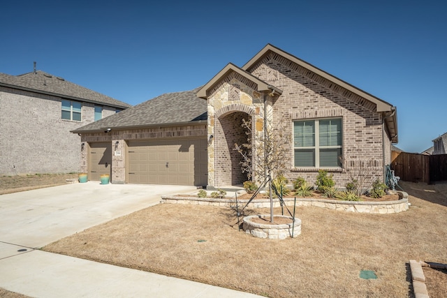 french country style house featuring brick siding, an attached garage, concrete driveway, and a shingled roof