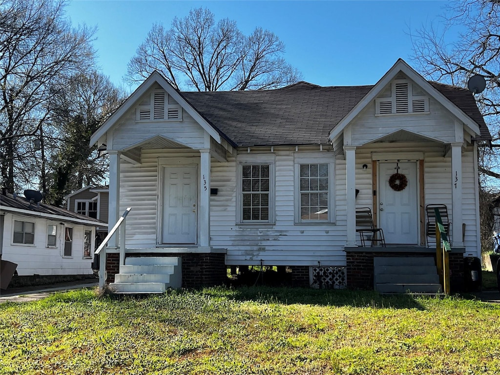 view of front of house with a front yard and roof with shingles