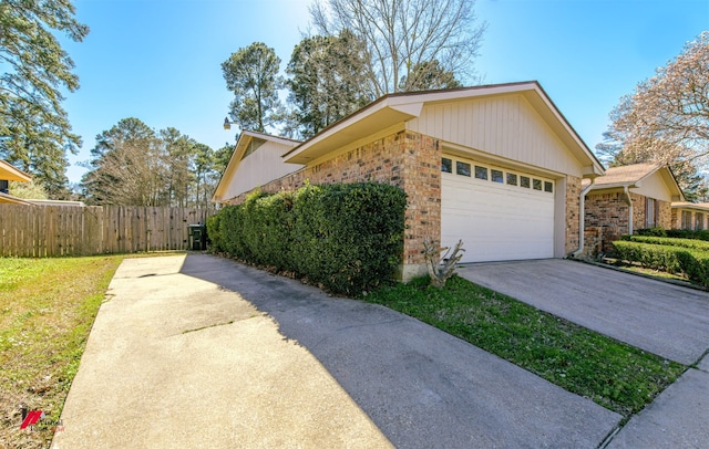 view of home's exterior featuring brick siding, an attached garage, concrete driveway, and fence