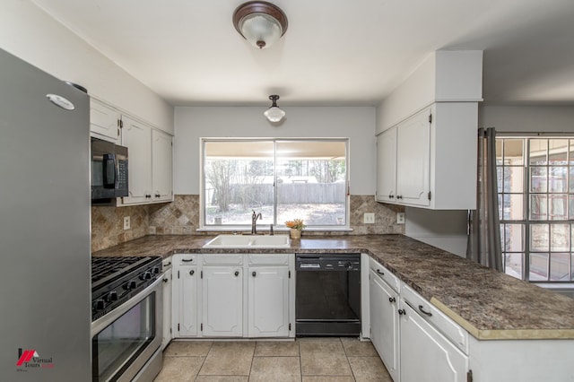 kitchen featuring dark countertops, appliances with stainless steel finishes, white cabinetry, and a sink