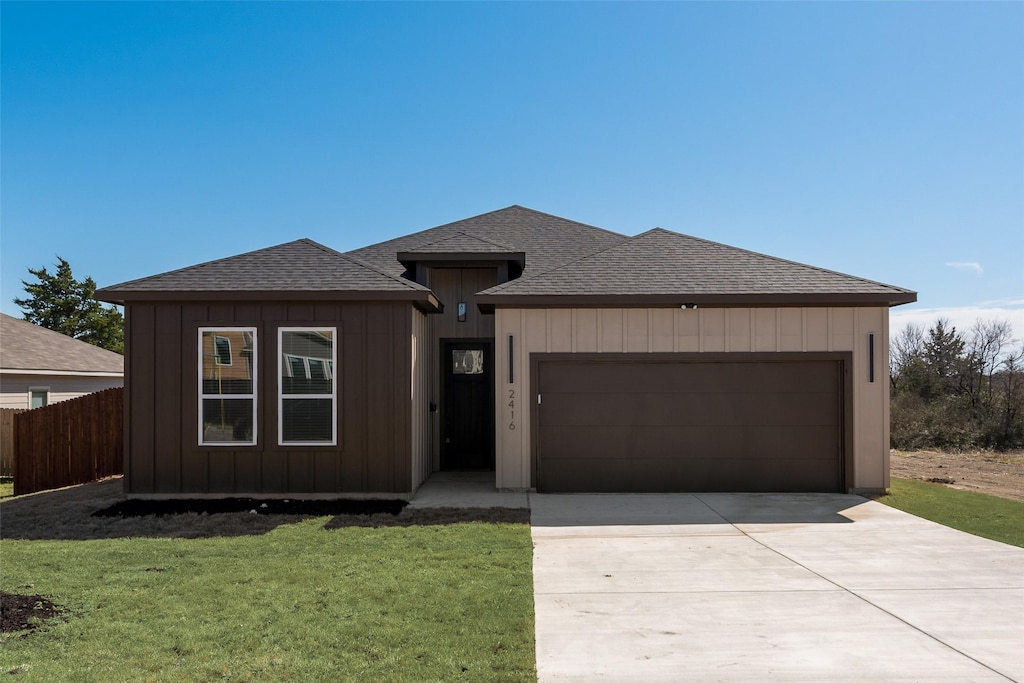 view of front of home with concrete driveway, fence, a garage, and a shingled roof