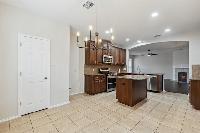 kitchen featuring visible vents, a peninsula, ceiling fan, appliances with stainless steel finishes, and a center island