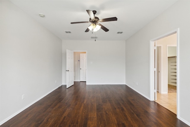 spare room with visible vents, dark wood-type flooring, and a ceiling fan