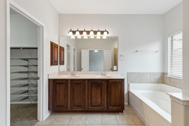 full bathroom featuring a garden tub, double vanity, tile patterned floors, and a sink