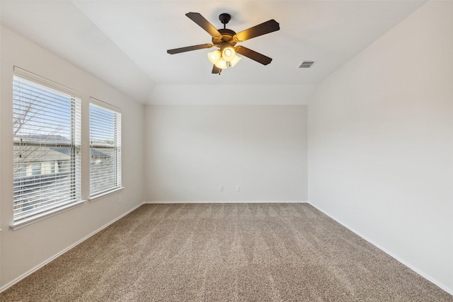 empty room featuring visible vents, a ceiling fan, carpet flooring, baseboards, and vaulted ceiling