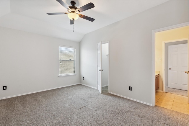 unfurnished bedroom with vaulted ceiling, light tile patterned floors, light colored carpet, and baseboards