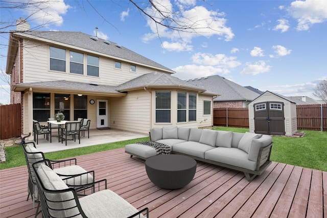 deck with an outbuilding, an outdoor living space, a fenced backyard, a yard, and a storage shed