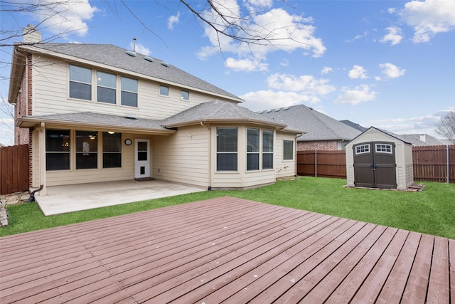 deck featuring an outbuilding, a lawn, a patio, a fenced backyard, and a shed