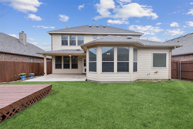 rear view of house with a patio, a yard, a fenced backyard, and a shingled roof