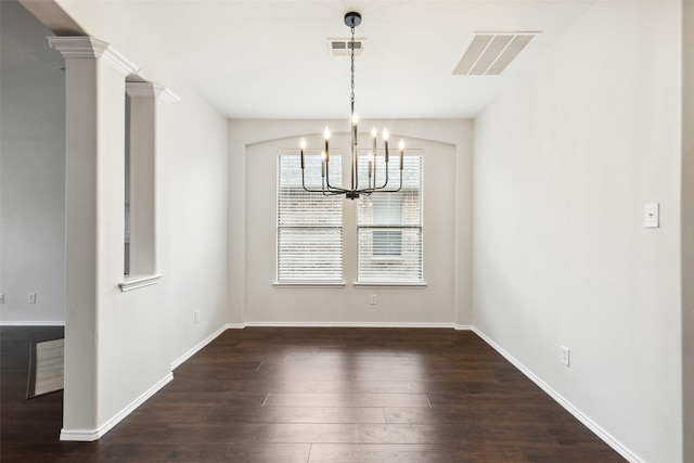 unfurnished dining area with visible vents, baseboards, dark wood finished floors, a chandelier, and decorative columns