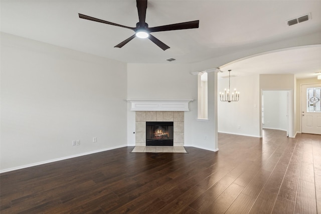 unfurnished living room with a tile fireplace, wood finished floors, visible vents, and arched walkways