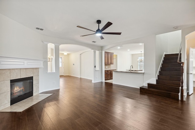 unfurnished living room featuring visible vents, dark wood-type flooring, a fireplace, and ornate columns