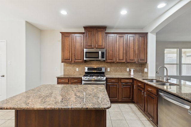 kitchen with tasteful backsplash, light stone countertops, light tile patterned floors, stainless steel appliances, and a sink