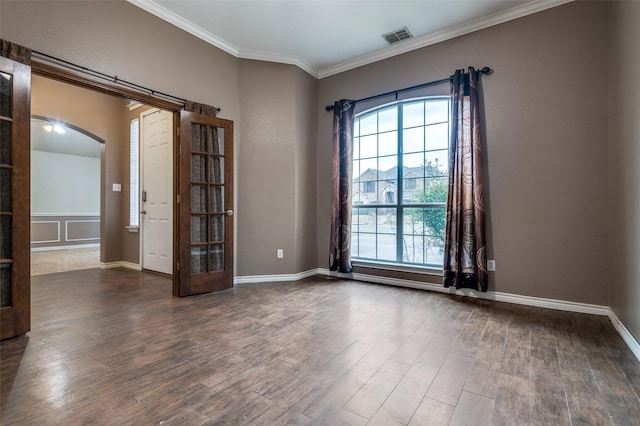 unfurnished room with visible vents, crown molding, baseboards, dark wood finished floors, and arched walkways