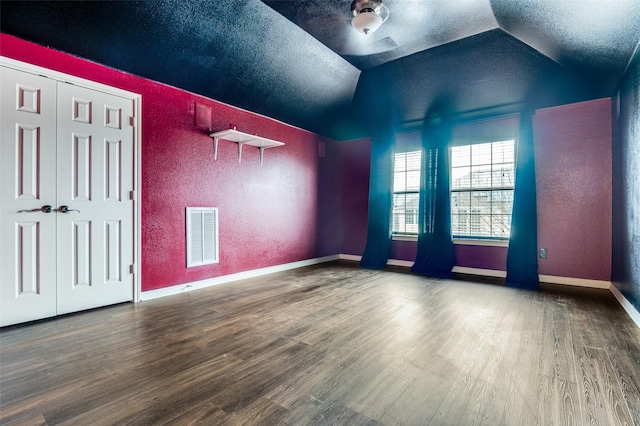 spare room featuring visible vents, a textured ceiling, wood finished floors, and vaulted ceiling