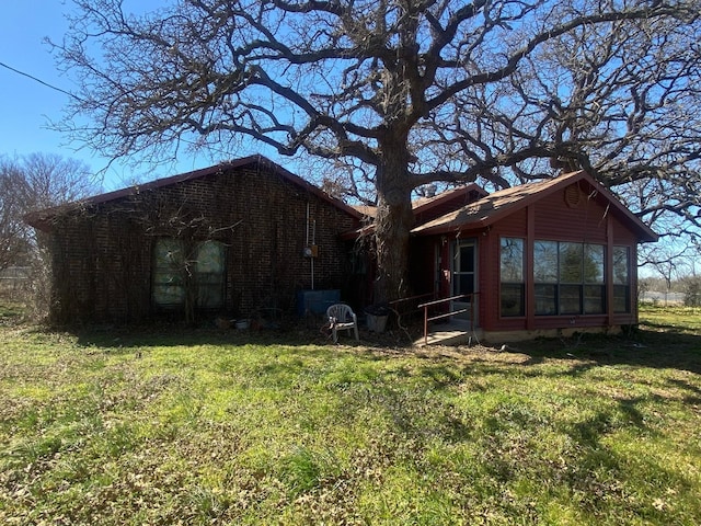 exterior space with a lawn, brick siding, and a sunroom