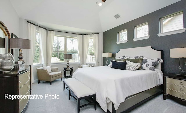 bedroom featuring visible vents, lofted ceiling, carpet floors, and an accent wall