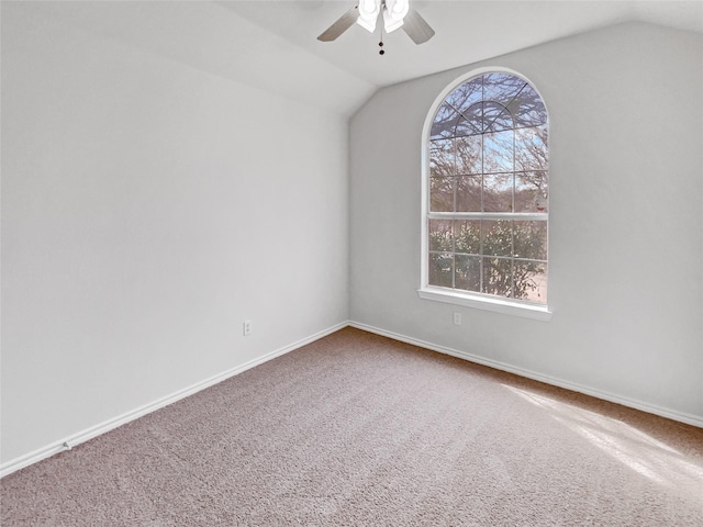 empty room featuring baseboards, ceiling fan, carpet flooring, and vaulted ceiling